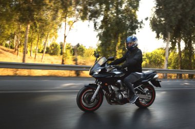 Otobanda hareket bulanıklığı olan bir motorcunun yan görüntüsü. 