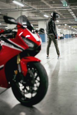 Bir motosiklet sürücüsünün araba parkında kasklı ve odakları çözülmüş bir motosiklet sürücüsü..