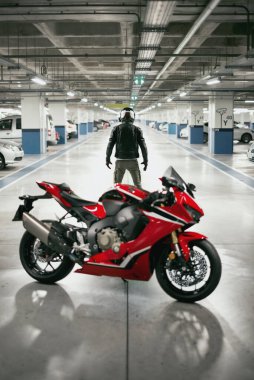 Bir motosiklet sürücüsünün araba parkında kasklı ve odakları çözülmüş bir motosiklet sürücüsü..