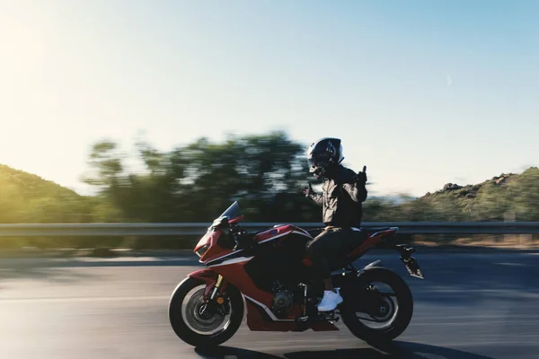 公路上骑红色摩托车的摩托车手的侧视图 没有手 动作模糊 — 图库照片