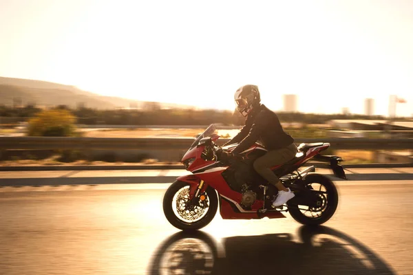 公路上骑红色摩托车的骑自行车者的侧视图 — 图库照片