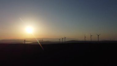 Tepedeki ve günbatımındaki yel değirmenlerinin insansız hava aracı görüntüleri.