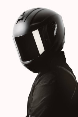 Beyaz arka planda siyah kaskla poz veren bir motosiklet sürücüsünün portresi.