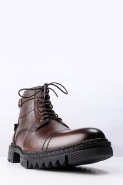 Beyaz arka planda kahverengi deri bir botun yakın plan çekimi..