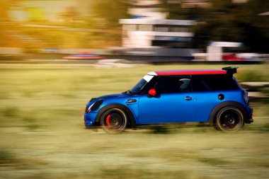 İzmir, Türkiye - 24 Eylül 2022: Hızlı giden Mavi renkli Mini Cooper spor arabası.