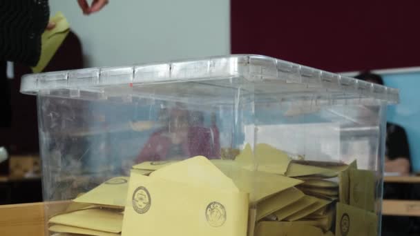 土耳其伊兹密尔 2023年5月14日 一名妇女在土耳其总统和议会选举中投票的特写视频 人们看到这个女人把选票扔进了一个透明的盒子里 背后有模糊的选举官员 — 图库视频影像