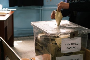 İzmir, Türkiye - 14 Mayıs 2023: Türkiye 'de yapılan cumhurbaşkanlığı ve parlamento seçimleri sırasında bir kadının oyunu sandığa attığı yakın çekim. Kadının kimliği görünürde yok, sadece oy verme sürecinde eli görülüyor.