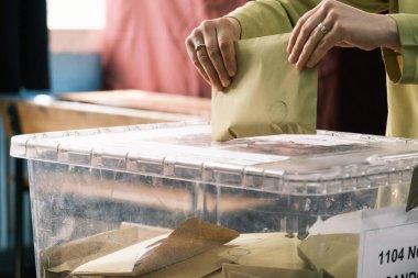 İzmir, Türkiye - 14 Mayıs 2023: Türkiye 'de yapılan cumhurbaşkanlığı ve parlamento seçimleri sırasında bir kadının oyunu sandığa attığı yakın çekim. Kadının kimliği görünürde yok, sadece oy verme sürecinde eli görülüyor.