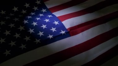 Amerikan bayrağına samimi, yavaş çekimde bir bakış, karanlığa karşı ışıkla aydınlatılmış..