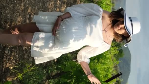 Μια Χαρούμενη Έγκυος Γυναίκα Λευκό Φόρεμα Και Καπέλο Αγγίζει Στοργικά — Αρχείο Βίντεο