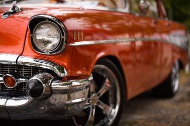 İzmir, Türkiye - 3 Haziran 2023: İzmir 'in Buca Pond kentinde düzenlenen IZKOD Classic Car Meet' te yağmura kapılmış far ve kısmen döndürülmüş turuncu 1957 Chevrolet Impala
