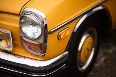İzmir, Türkiye - 3 Haziran 2023: Buca Pond 'daki IZKOD Klasik Otomobil Buluşması' nda, yağmur damlalarıyla kaplı 1970 model sarı bir Mercedes 'e yakın çekim