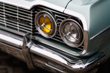 İzmir, Türkiye - 3 Haziran 2023: İzmir 'in Buca Pond kentinde düzenlenen IZKOD Klasik Araba Buluşması' nda yağmura kapılmış yeşil bir Chevrolet Impala 'nın farının yakın çekimi.