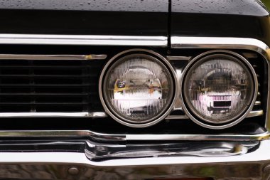 İzmir, Türkiye - 3 Haziran 2023: Yağmurla kaplı siyah bir Chevrolet Chevelle SS 'in farının yakın çekimi