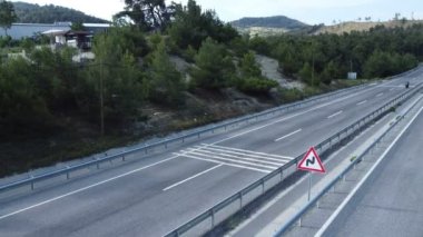 Bir yarış motosikletinin tekerlek sürerken ve otobanda sollarken çekilmiş büyüleyici drone görüntüleri. İnsansız hava aracı sabit duruyor, yüksek hızlı geçişi ve motor sporunun heyecanını yakalıyor.