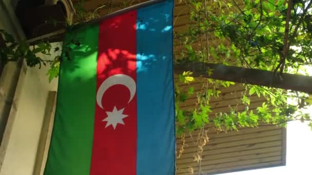 ぶどうの木を吊るすと涼しい木陰ができるバクーの一里貝の平和な路地を描いた映像 アゼルバイジャン国旗が優しく波立ち 地元の魅力に国の誇りを加えています — ストック動画