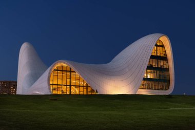 Bakü, Azerbaycan - 25 Haziran 2023: Alacakaranlık Gökyüzüne karşı hazırlanan Heydar Aliyev Merkezi 'nin etkileyici mimarisinin akşam görüntüsü