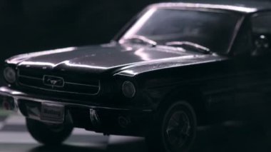 İzmir, Türkiye - 13 Mart 2023: Klasik siyah Ford Mustang 260 'ın gizemli bir sisle kaplandığını gösteren görsel olarak çarpıcı bir video. Araç, siyah arka planda kareli bir zeminde, olay yerine derinlik ve entrika ekliyor..