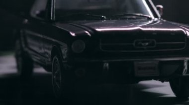 İzmir, Türkiye - 13 Mart 2023: Klasik siyah Ford Mustang 260 'ın gizemli bir sisle kaplandığını gösteren görsel olarak çarpıcı bir video. Araç, siyah arka planda kareli bir zeminde, olay yerine derinlik ve entrika ekliyor..
