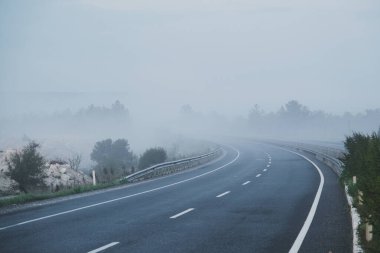 Sabahın erken saatlerinde çekilen film sahnesine benzeyen dramatik bir sahne. Yoğun sisle kaplı dolambaçlı bir yol düşük bir görünürlük atmosferi yaratıyor ve manzaraya biraz gizem katıyor.