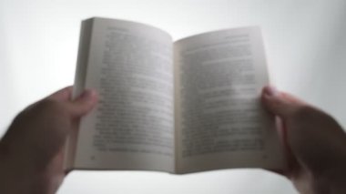 Beyaz bir arkaplan üzerine bir kitap okuyorum. Kitabın dikkati dağılmış..
