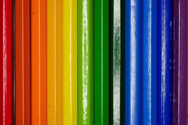 A photo of colorful pencils lined up, ends unseen, showcasing a continuous flow of vibrant hues and unity in diversity.