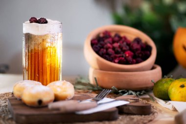 Üç böğürtlenli köpüklü elma suyunun ortasında, çikolata dolu bir kurabiye, çatal bıçak takımı, mandalina ve bir Jack O 'Lantern ile çevrili..