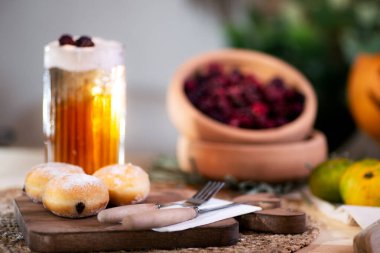 Kesme tahtasında çatal bıçaklı çikolatalı kurabiye, köpüklü elma suyu, kırmızı böğürtlen, mandalina ve arka planda bir Jack O 'Lantern ile servis edilir..