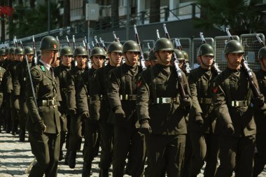 İzmir, Türkiye - 30 Ağustos 2023: Yeşil üniformalı askerler, Zafer Günü geçit töreninde Türk ordusunun disiplinini örnek alarak mükemmel bir uyum içinde yürüdüler.