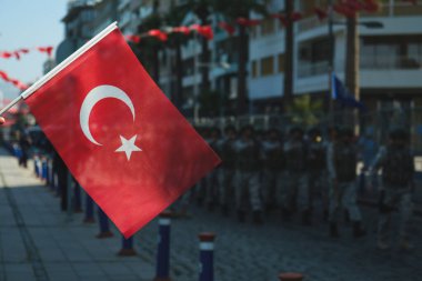 30 Ağustos 2023 'te İzmir Kordon' da çekilen bu çarpıcı fotoğrafta ön planda canlı renkli bir Türk bayrağı yer alıyor. Arka planda, yüzeysel bir alan derinliği nedeniyle biraz bulanık, askerler C 'de yürürken görülebilir.