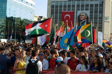 İzmir, Türkiye - 1 Eylül 2023 Belediye Başkanı Tun Soyer, İzmir Uluslararası Fuarı 'nın açılış kortejinde neşeli kalabalığın yanında gururla yürüyor. Çeşitli ulusların bayrakları dalgalanıyor, gökyüzünde balonlar uçuşurken