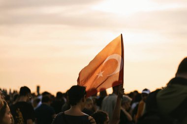 İzmir, Türkiye - 9 Eylül 2023: Cumhuriyet Meydanı 'nda coşkulu insanlar denizi ortasında, İzmir' in kurtuluşunu kutlayan bir kişi gururla Türk bayrağını kaldırdı