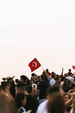 İzmir, Türkiye - 9 Eylül 2023: Cumhuriyet Meydanı 'nda coşkulu insanlar denizi ortasında, İzmir' in kurtuluşunu kutlayan bir kişi gururla Türk bayrağını kaldırdı