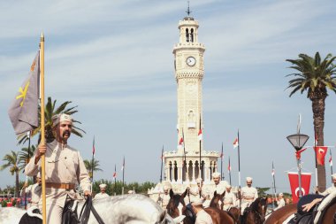 İzmir, Türkiye, Eylül, 9, 2023, Süvariler şehrin özgürlüğünü simgeleyen ikonik İzmir Saat Kulesi önünde binicilik becerilerini gururla sergiliyorlar. Günün tarihsel önemini kutlamak için poz veriyorlar.