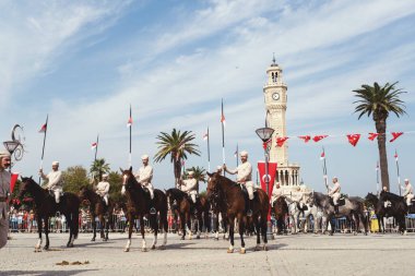 İzmir, Türkiye, Eylül, 9, 2023, Süvariler şehrin özgürlüğünü simgeleyen ikonik İzmir Saat Kulesi önünde binicilik becerilerini gururla sergiliyorlar. Günün tarihsel önemini kutlamak için poz veriyorlar.