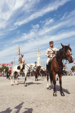 İzmir, Türkiye, Eylül, 9, 2023, Süvariler şehrin özgürlüğünü simgeleyen ikonik İzmir Saat Kulesi önünde binicilik becerilerini gururla sergiliyorlar. Günün tarihsel önemini kutlamak için poz veriyorlar.