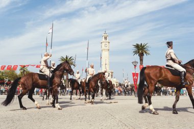 İzmir, Türkiye, Eylül, 9, 2023, Süvariler şehrin özgürlüğünü simgeleyen ikonik İzmir Saat Kulesi önünde binicilik becerilerini gururla sergiliyorlar. Günün tarihsel önemini kutlamak için poz veriyorlar.