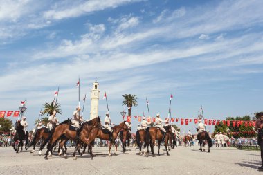 İzmir, Türkiye, Eylül, 9, 2023, Süvariler şehrin özgürlüğünü simgeleyen ikonik İzmir Saat Kulesi önünde binicilik becerilerini gururla sergiliyorlar. Günün tarihsel önemini kutlamak için poz veriyorlar.