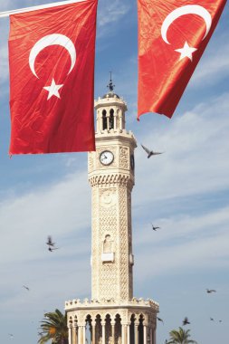 İzmir, Türkiye, Eylül, 9, 2023, Konak Meydanı 'ndaki ikonik saat kulesinin büyüleyici görüntüsü, Türk bayrakları sahneyi süslüyor, tarihi yapının yanı sıra ulusal gururu da sergiliyor.