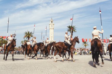 İzmir, Türkiye, Eylül, 9, 2023, Süvariler şehrin özgürlüğünü simgeleyen ikonik İzmir Saat Kulesi önünde binicilik becerilerini gururla sergiliyorlar. Günün tarihsel önemini kutlamak için poz veriyorlar.