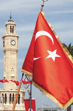 İzmir, Türkiye, 9 Eylül 2023: İzmir 'in ünlü Saat Kulesi' nin arkaplanda zarif bir şekilde durduğu bir Türk bayrağını sallayan canlı bir fotoğraf