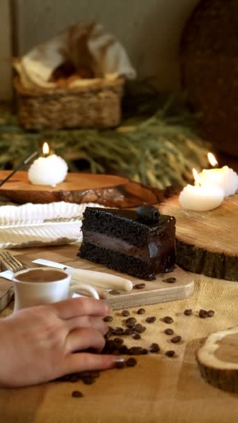 一个4K的垂直视频捕捉到了一个女人的手 她轻轻地把一杯土耳其咖啡放在一块巧克力蛋糕旁边 上面有木制的餐具 所有这些都放在一个乡村的背景上 营造出一种舒适迷人的氛围 — 图库视频影像