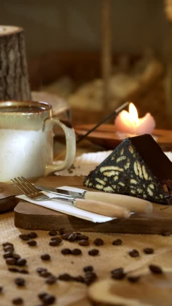 一个4K电影风格的视频展示了一个美味的马赛克蛋糕在柳条布和木制切割板 在背景音乐中 一杯热气腾腾的杯子 燃烧着的蜡烛和熏香使现场的气氛更加温暖 更令人心旷神怡 — 图库视频影像