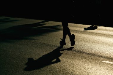 İzmir, Türkiye, 10 Eylül 2023: Koşucular İzmir Maratonu sırasında asfalt üzerindeki parlak güneş ışığına karşı siluet haline geldiler