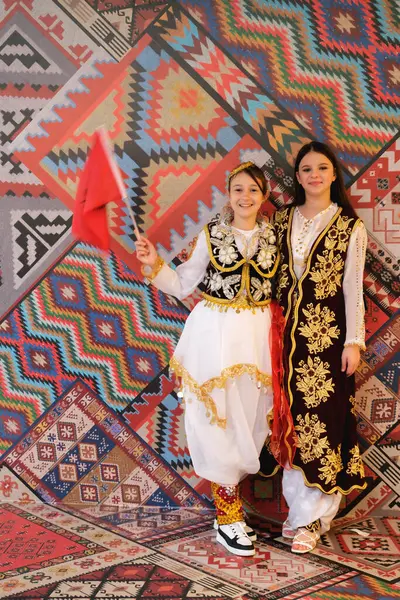 11月28日 阿尔巴尼亚地拉那 独立日期间 两名拿着阿尔巴尼亚国旗的女孩在议会宫的传统模式前摆姿势 — 图库照片
