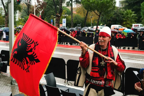 アルバニアのティラナ 11月28日 伝統的なドレスの高齢者は マザーテレサ宮殿の近くで独立記念日の祝賀会中にアルバニアの旗を保持しながらインタビューを与えます — ストック写真