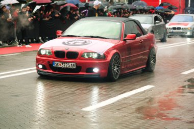 Tiran, Arnavutluk - 28 Kasım 2023: Ulusun Şehitleri Bulvarı 'nda, vatandaşlar yağmurlu bir Bağımsızlık Günü' nde üzerinde kırmızı BMW 3 / 46 etiket bulunan Cair Akort Ekibi 'nin yer aldığı modifiye edilmiş bir araç geçidini izliyorlar.