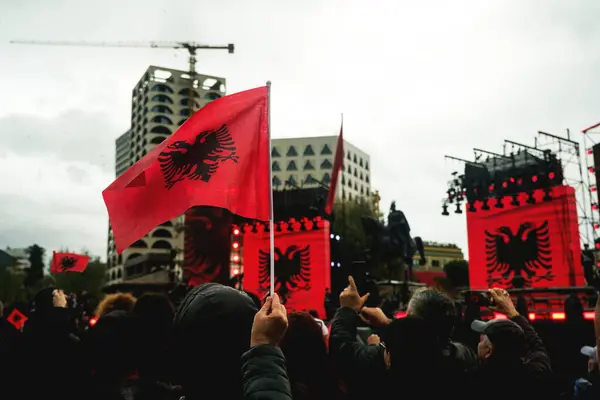 阿尔巴尼亚地拉那 2023年11月28日 在一个下雨天的独立日 在斯堪的纳维亚广场 一位身着阿尔巴尼亚传统服饰的妇女与一面阿尔巴尼亚国旗欢快地跳舞 她张开双臂 像一群拿着雨伞手表的人群一样 与国家历史博物馆共舞 — 图库照片