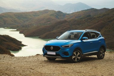 Tirana, Albania - November 30, 2023: Left front angle photo of a blue 2023 MG ZS SUV, taken with Lake Bovilla in the background