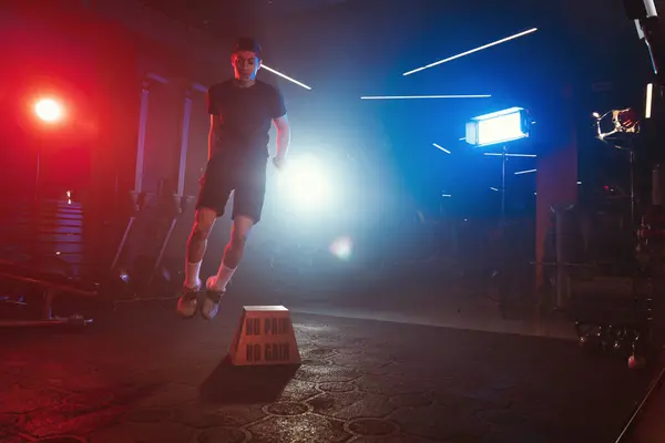 운동선수는 파란색과 빨간색 조명과 부드러운 안개가 체육관 속에서 울리는 점프를 스톡 사진